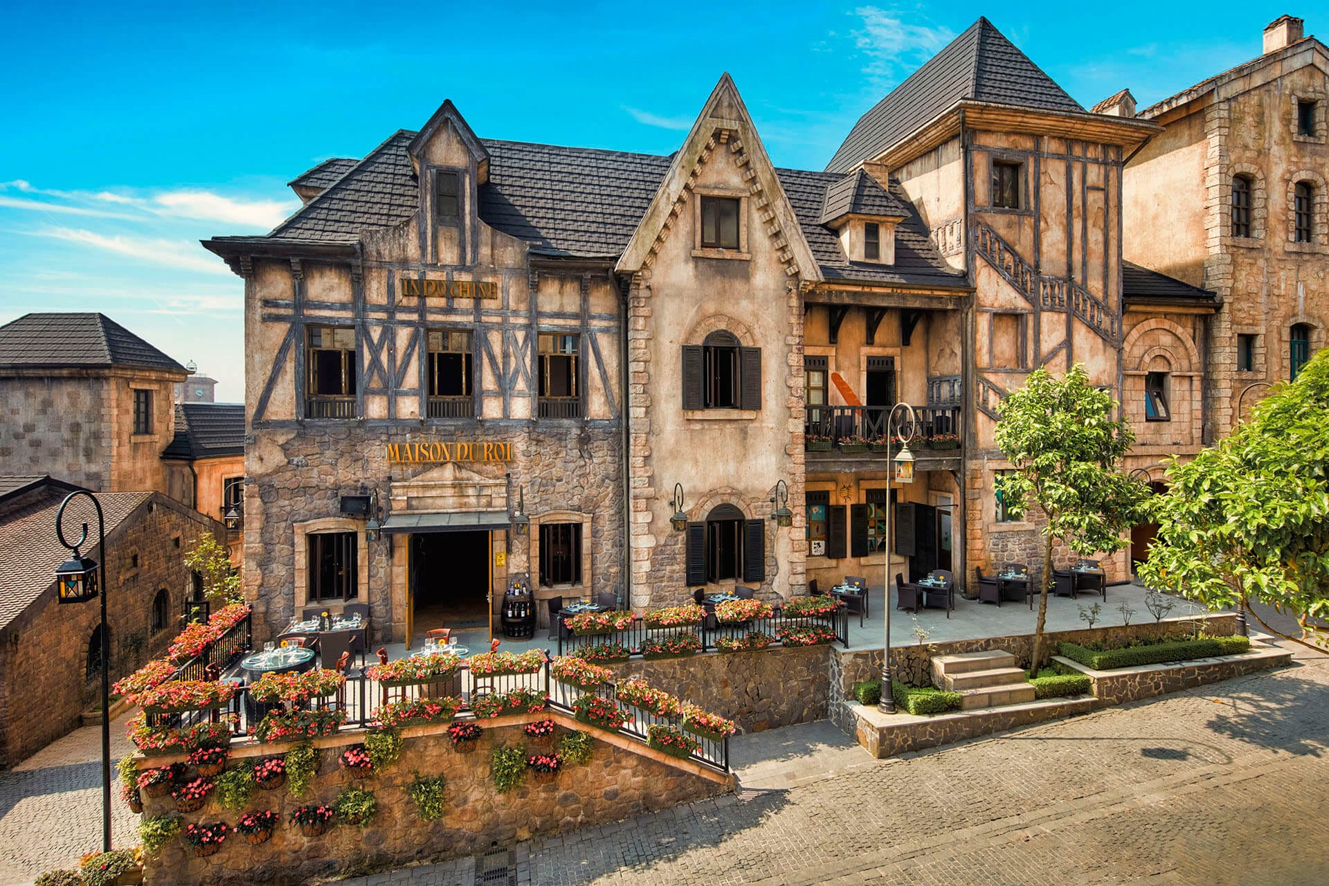 The charming French Village, bathed in the morning sunlight, is surrounded by a vibrant garden of colorful flowers 